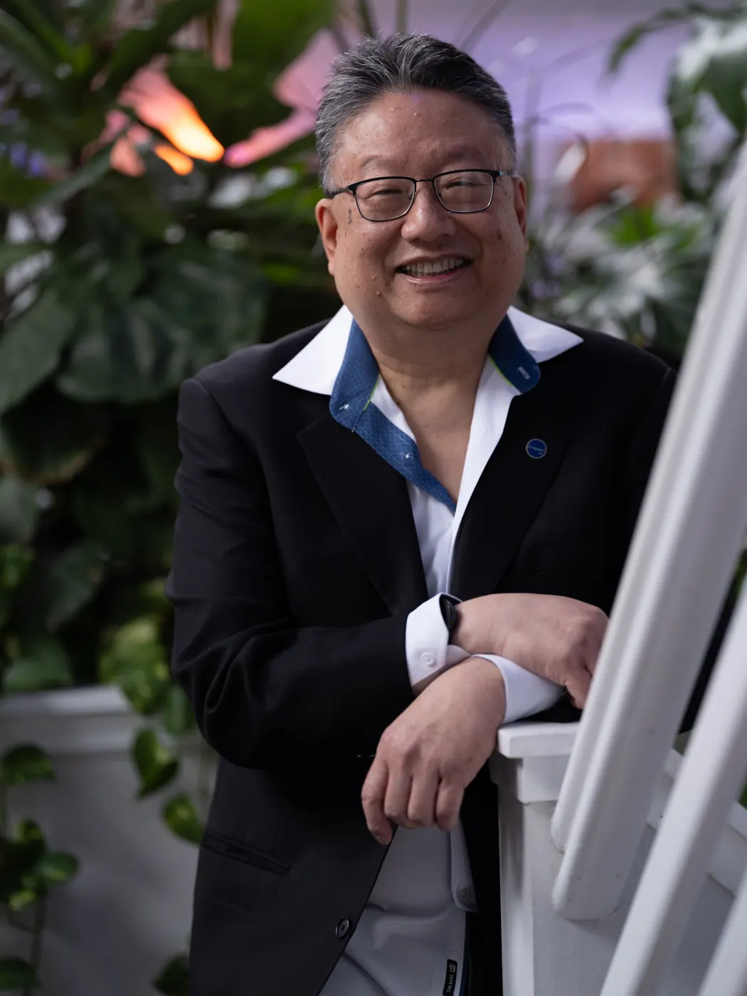 Steve Nye in his greenhouse, leaning on a white stair rail