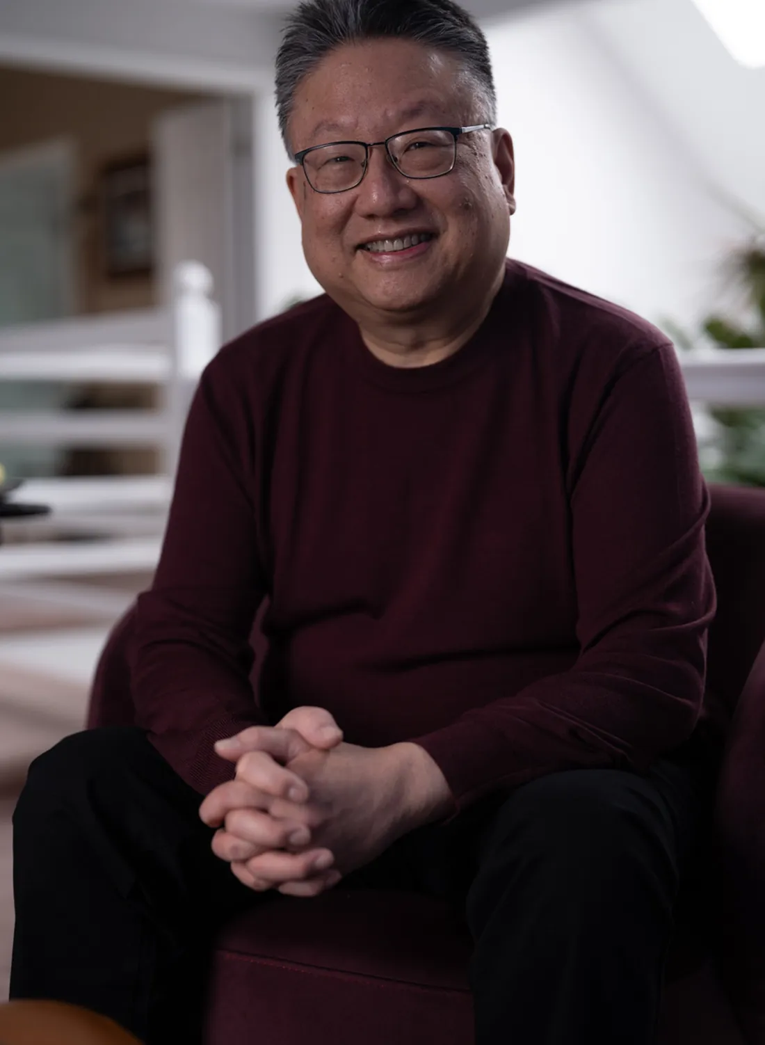 Steve Nye seated, hands clasped, looking at the camera